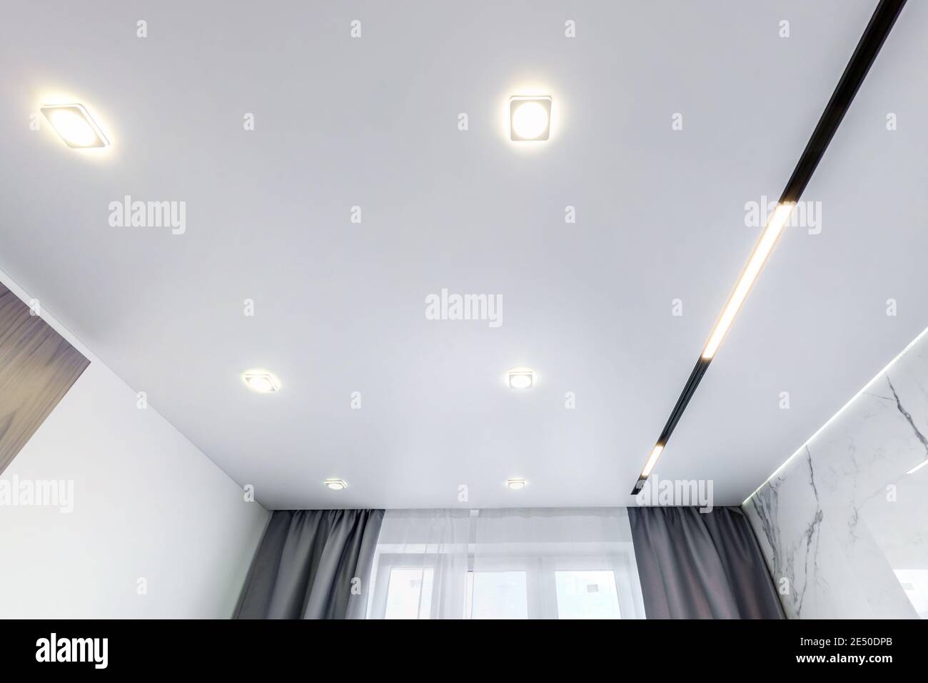 Abgehängte Decke mit Halogenstrahlern und Trockenmauerkonstruktion im leeren Raum in Wohnung oder Haus. Stretchdecke weiß und komplex. Stockfoto