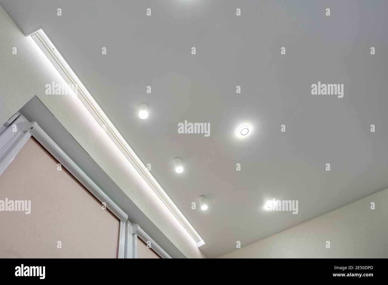 Abgehängte Decke mit Halogenstrahlern und Trockenmauerkonstruktion im leeren Raum in Wohnung oder Haus. Stretchdecke weiß und komplex. Stockfoto