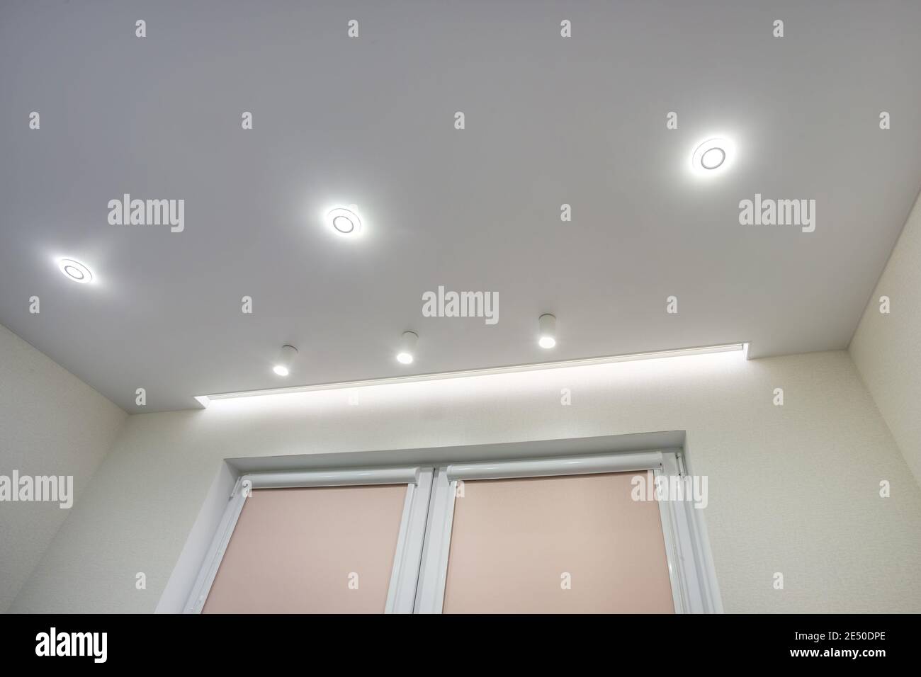 Abgehängte Decke mit Halogenstrahlern und Trockenmauerkonstruktion im leeren Raum in Wohnung oder Haus. Stretchdecke weiß und komplex. Stockfoto