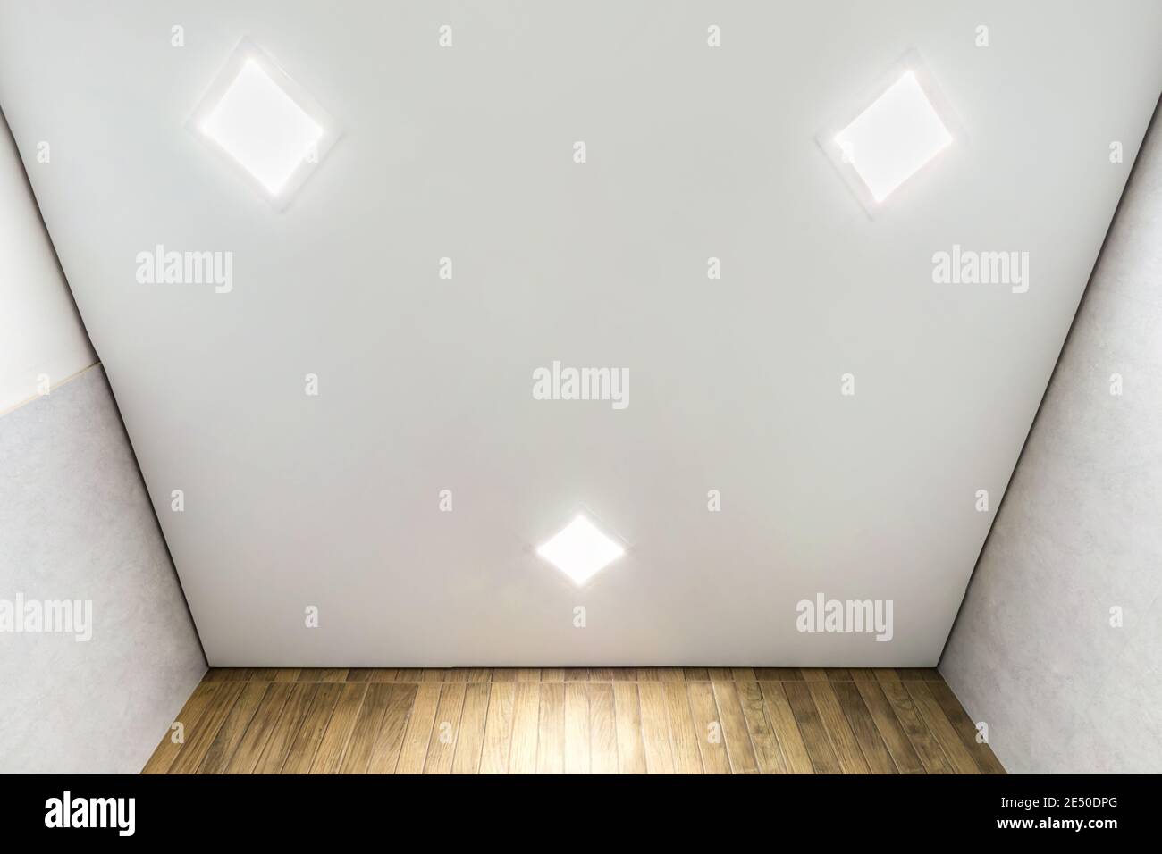 Abgehängte Decke mit Halogenstrahlern und Trockenmauerkonstruktion im leeren Raum in Wohnung oder Haus. Stretchdecke weiß und komplex. Stockfoto