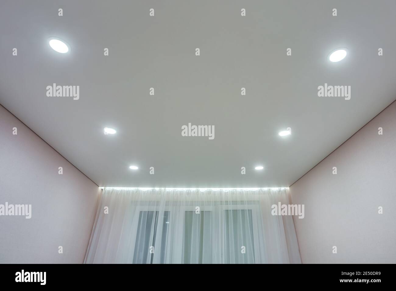 Abgehängte Decke mit Halogenstrahlern und Trockenmauerkonstruktion im leeren Raum in Wohnung oder Haus. Stretchdecke weiß und komplex. Stockfoto