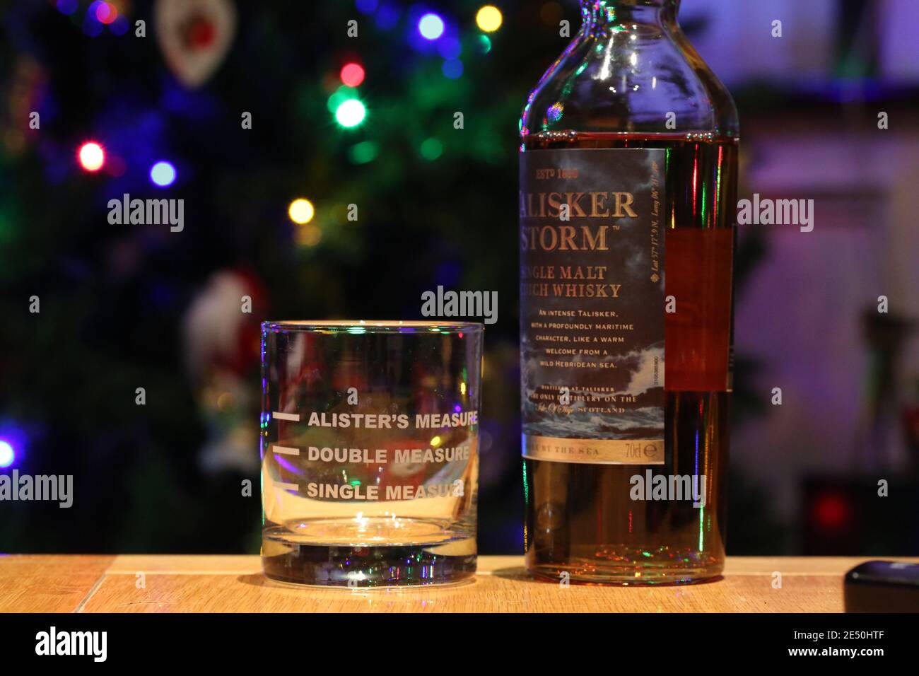 Whisky-Glas mit drei Maßnahmen markiert auf einer Flasche talisker Storm Single Malt Whisky, weihnachtsbaum Licht im Hintergrund Stockfoto