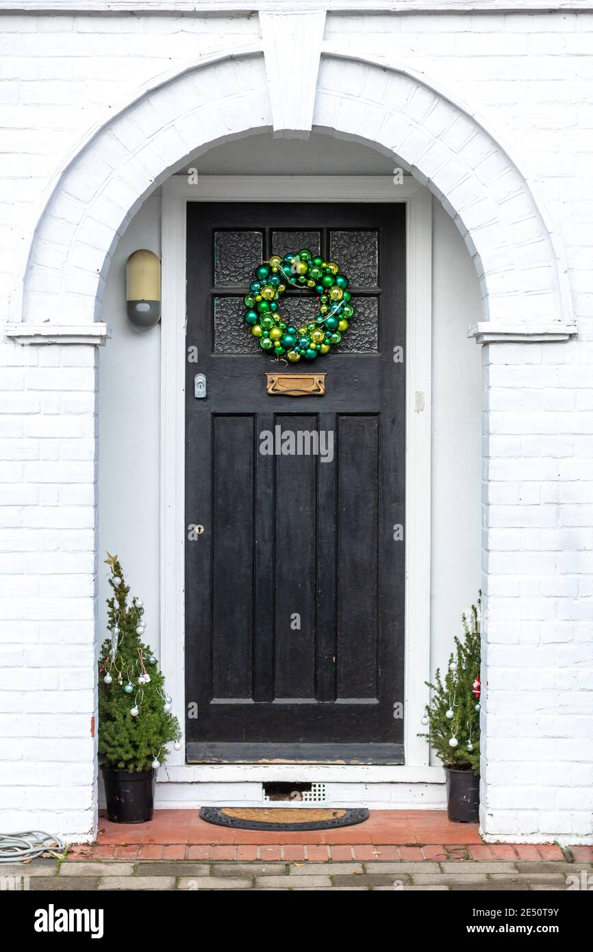 Grüne Kugeln bilden einen Weihnachtskranz an einer Haustür Unter einer Nische Stockfoto