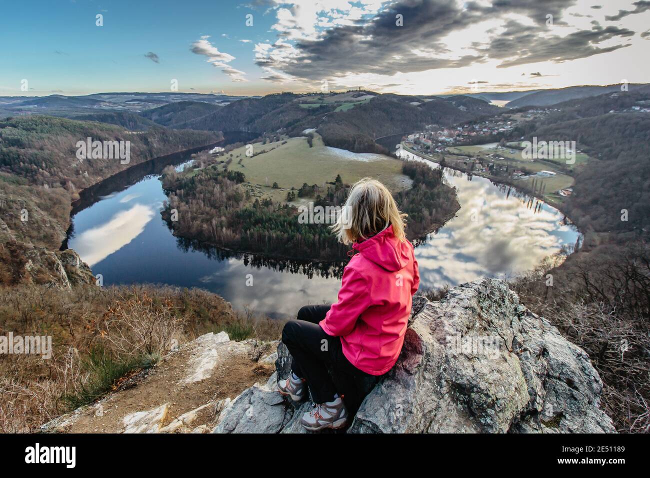 Glückliche Frau sitzt auf einer Klippe und genießen Sie den Blick auf den Fluss.Moldau Hufeisenform Mäander aus Solenice Aussichtspunkt, Tschechische Republik.schöne Landschaft Stockfoto