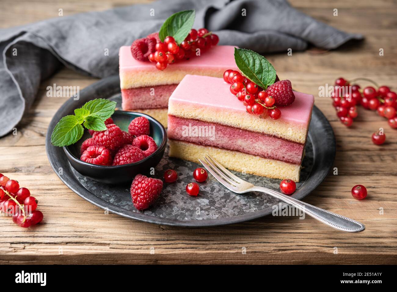 Köstliche und erfrischende saftige Dessert, Punch Cake mit Zuckerzuckerguss und frischen Himbeeren und roten Johannisbeeren auf Holz Hintergrund gekrönt Stockfoto
