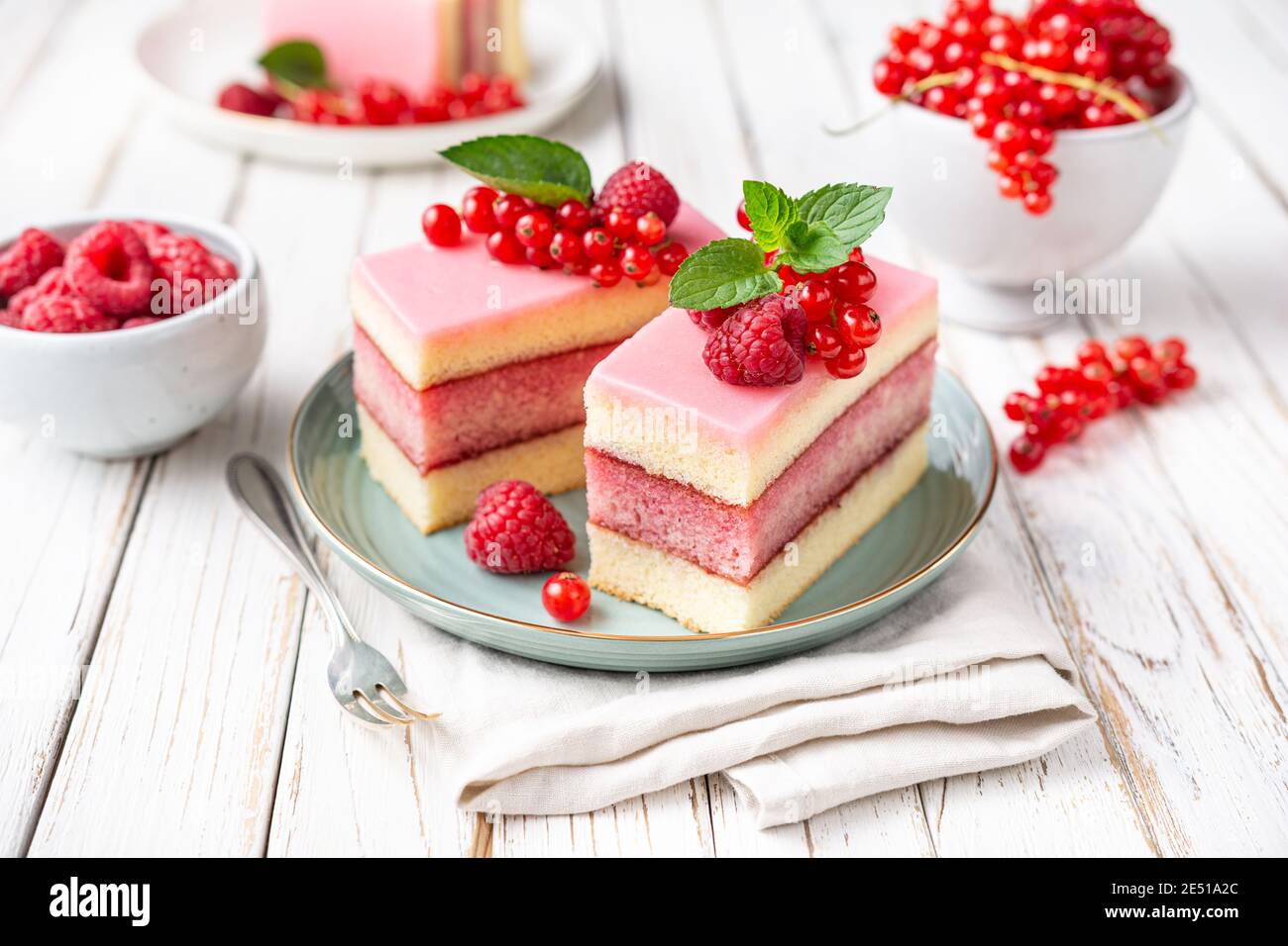 Köstliche und erfrischende saftige Dessert, Punch Cake mit Zuckerzuckerguss und frischen Himbeeren und roten Johannisbeeren auf Holz Hintergrund gekrönt Stockfoto