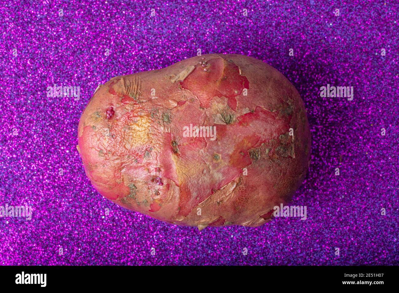 Rote Kartoffel auf glitzerndem Lila Hintergrund. Makroaufnahme Aus Der Luft. Stockfoto