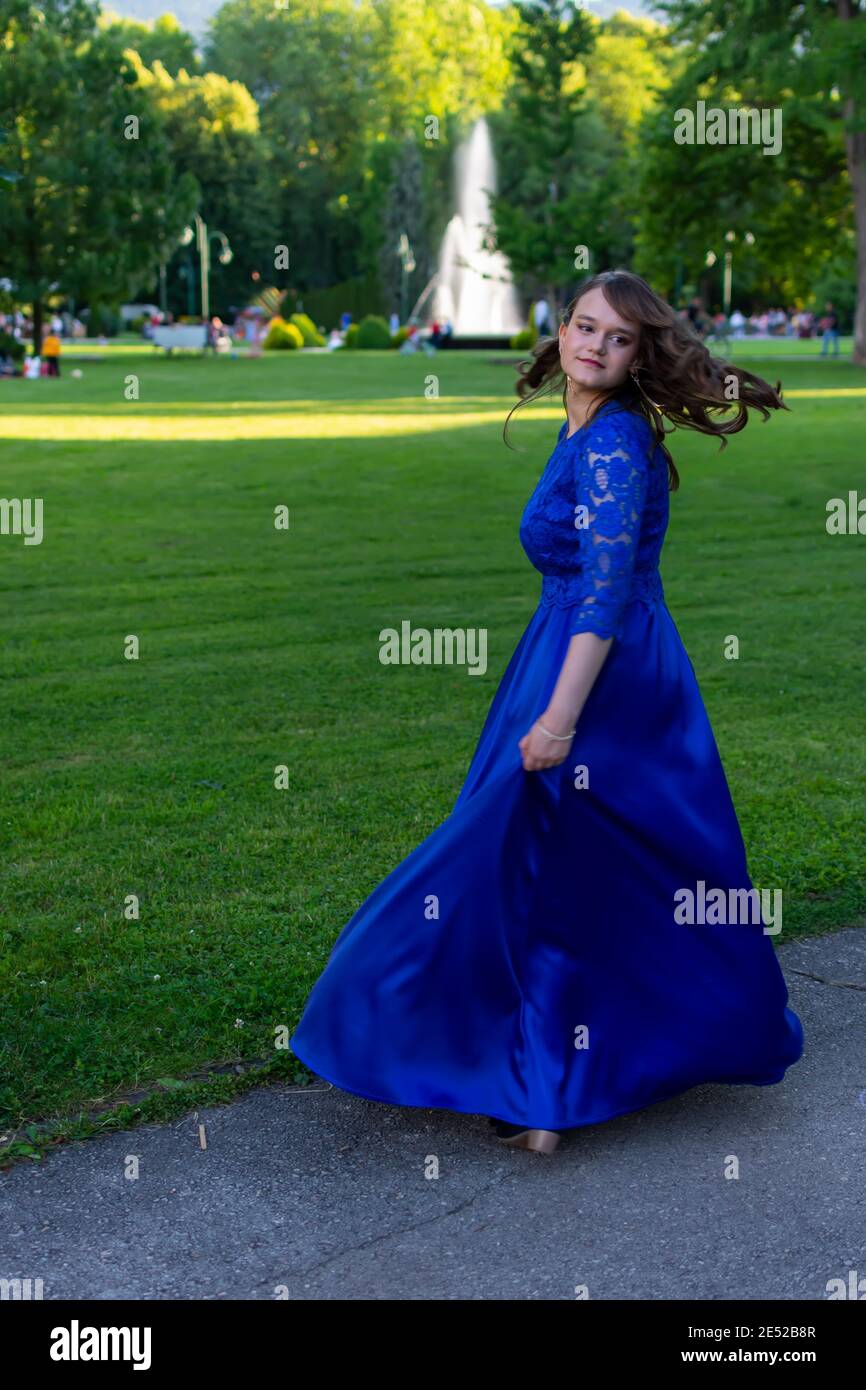 Prom Mädchen Spinnen in einem modernen und eleganten blauen Kleid. Entzückendes und modisches Outfit. Schönes Foto aus der Natur für die Abschlussfeier Stockfoto