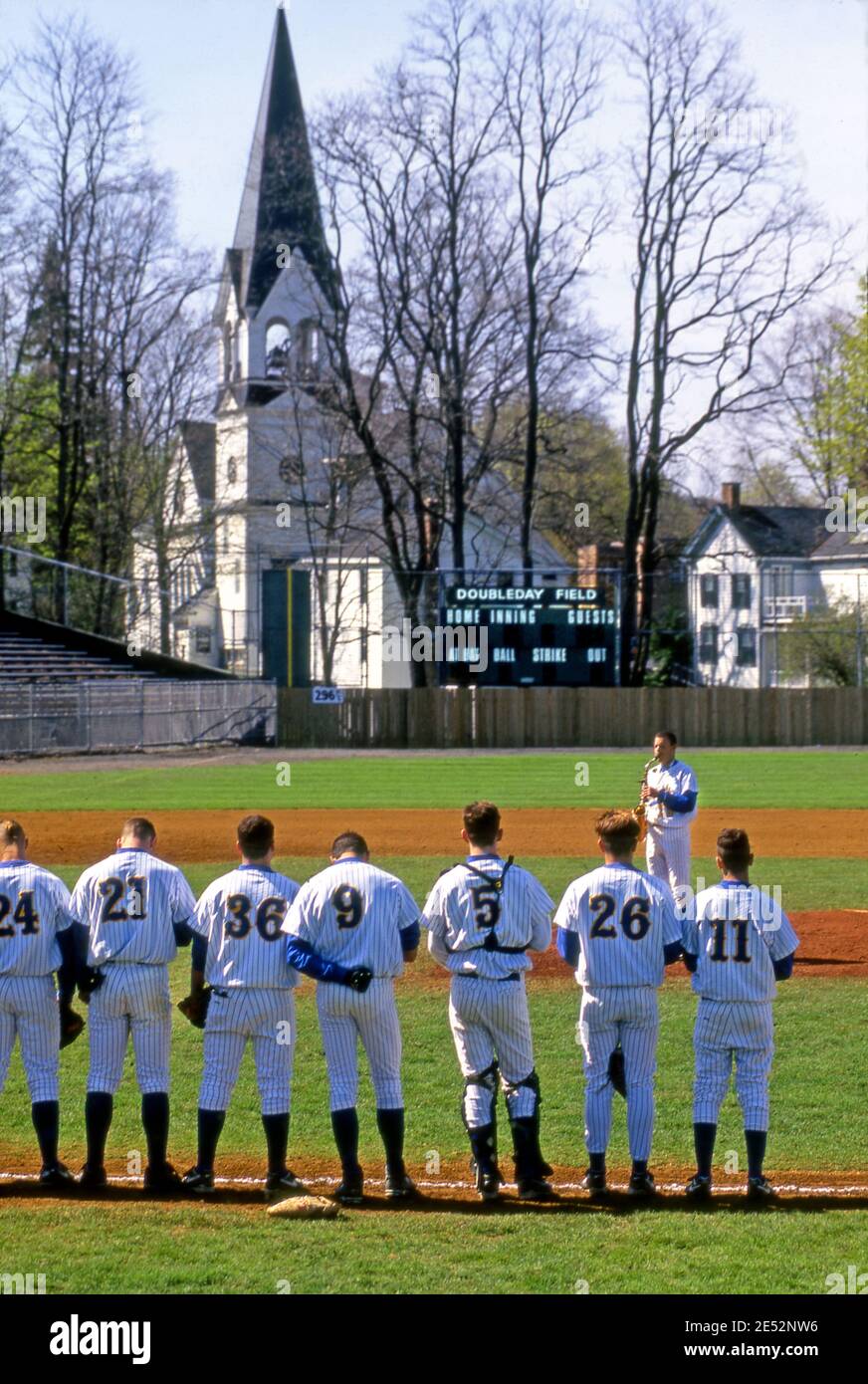 Baseball-Spieler stehen für die National Anthem von Saxophonist vor dem Start gespielt ofg ein Spiel im Doubleday Field in Copperstown, NY Stockfoto