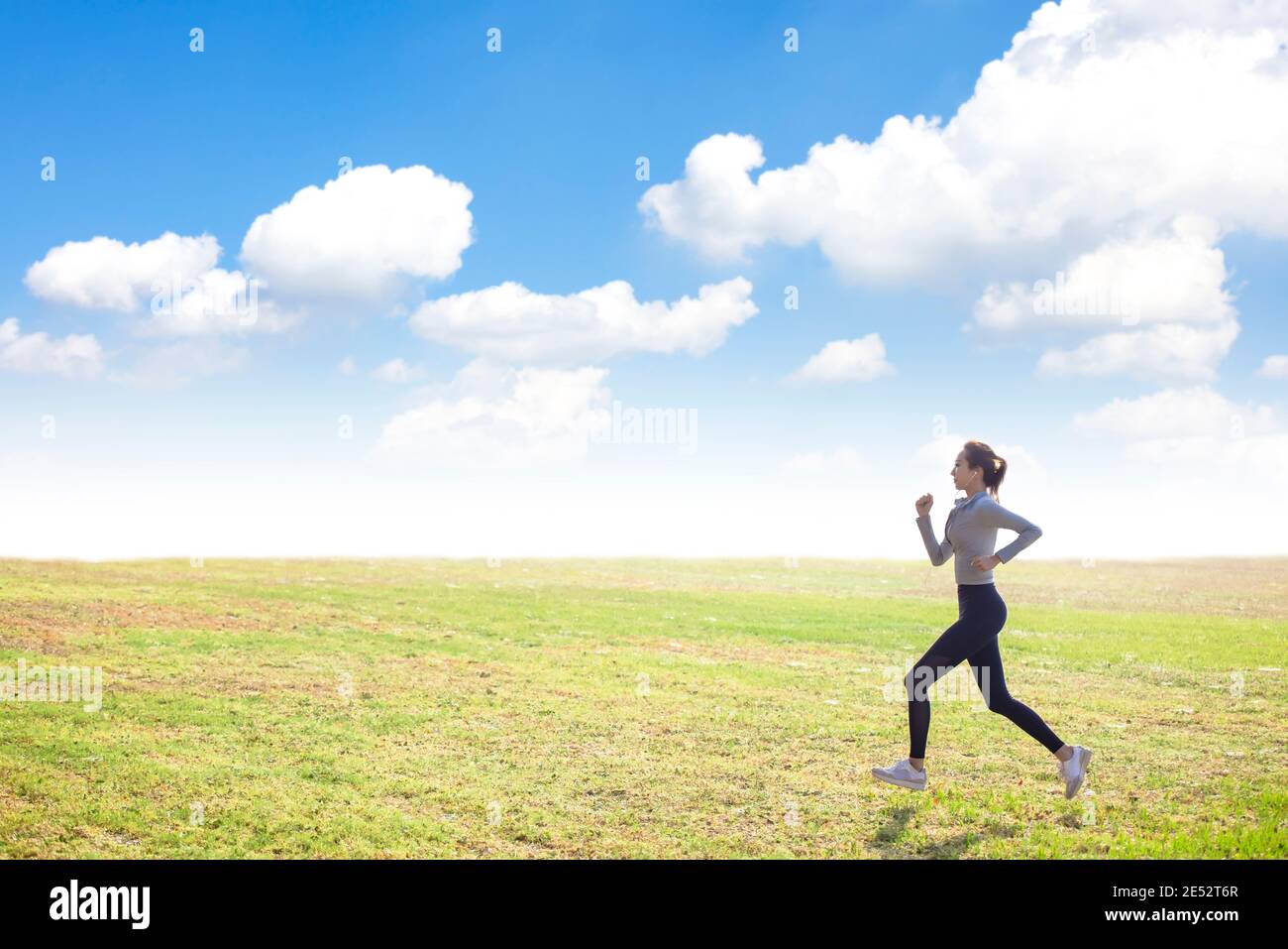 Junge schlanke Sportfrau läuft auf dem Grasfeld Stockfoto