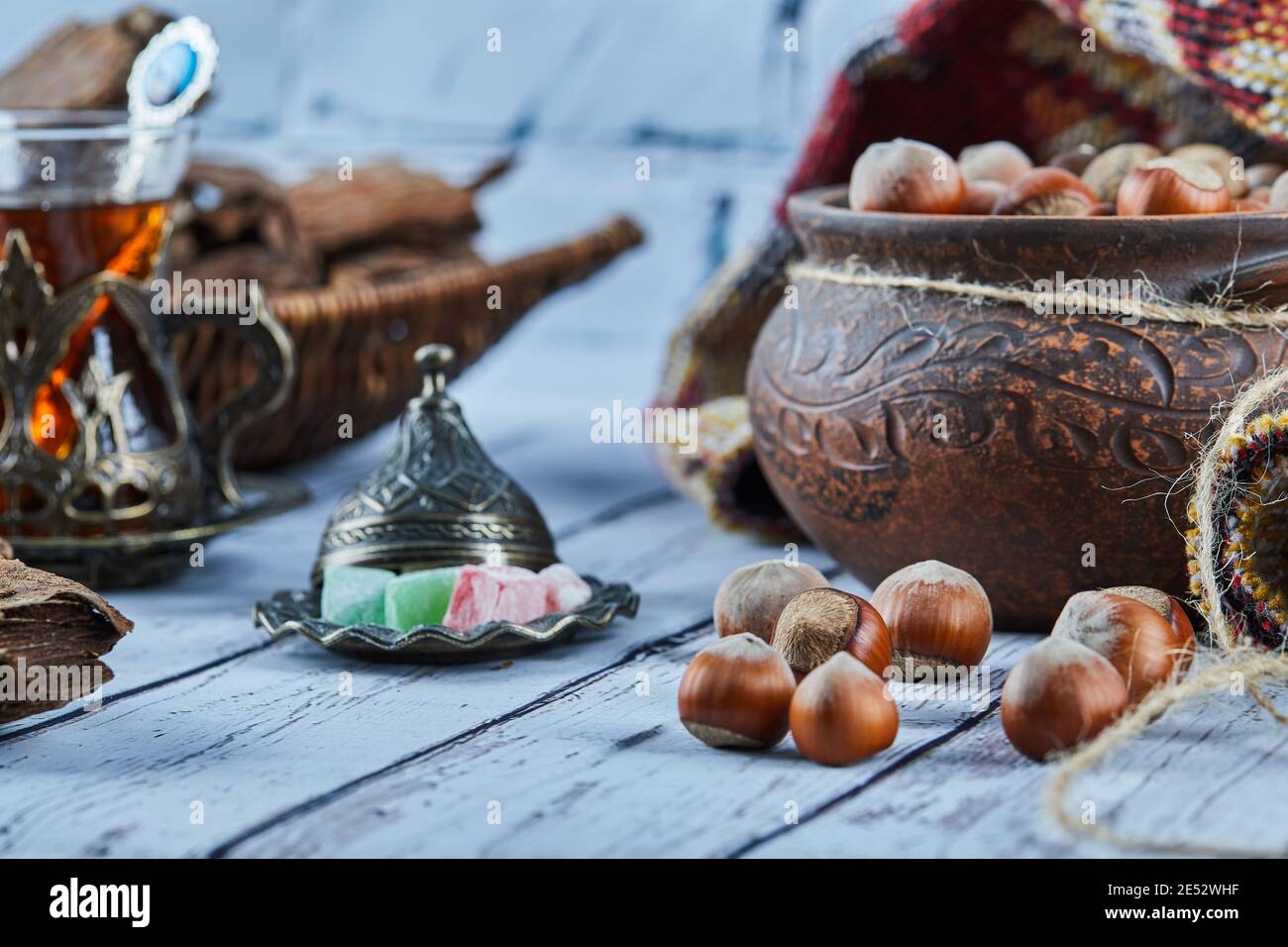 Eine Schale Haselnüsse auf blauem Holztisch mit Süßigkeiten Stockfoto