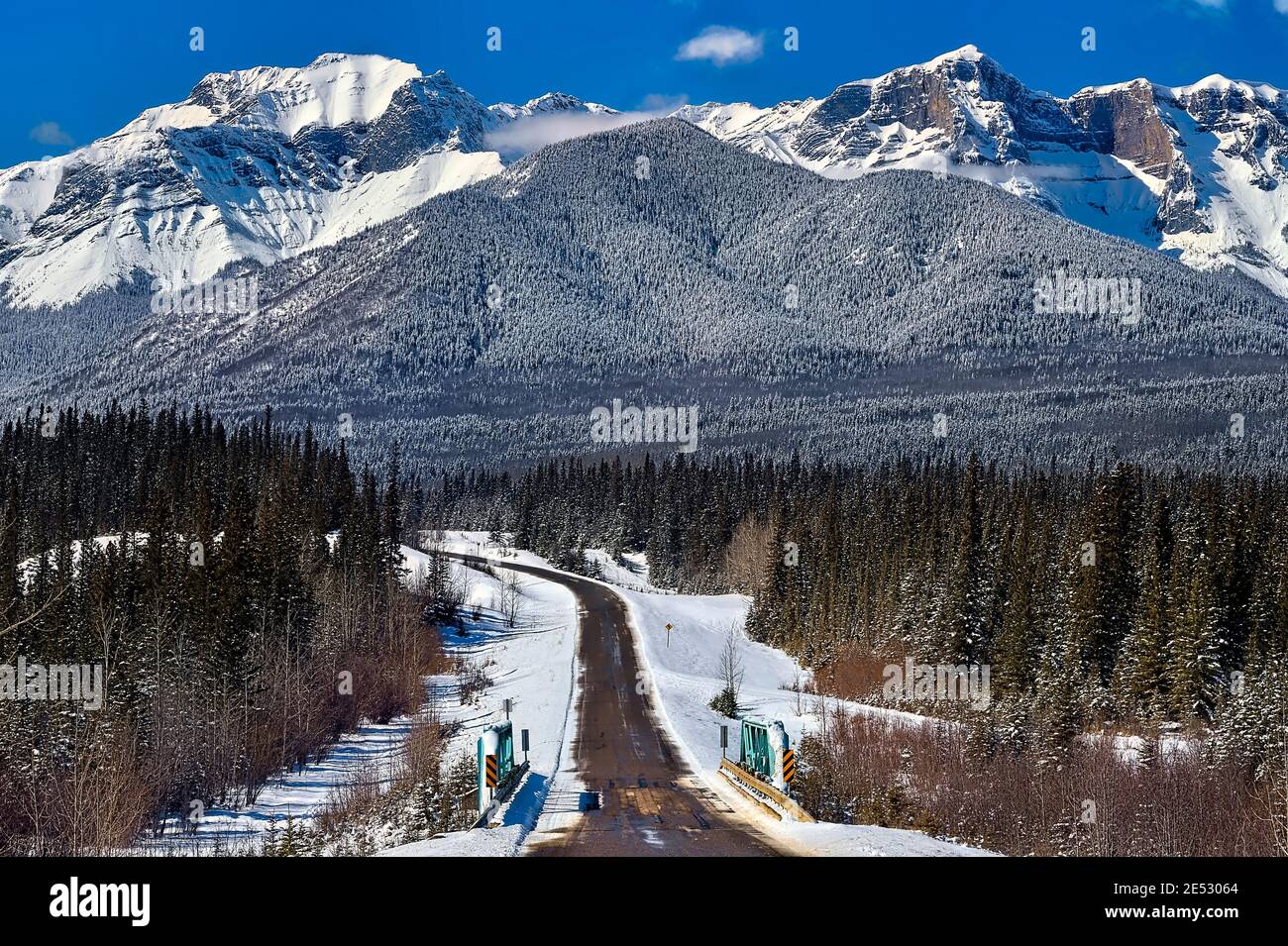Eine zweispurige Autobahn, die zu den schneebedeckten felsigen Bergen führt In der Stadt Brule im ländlichen Alberta Kanada Stockfoto