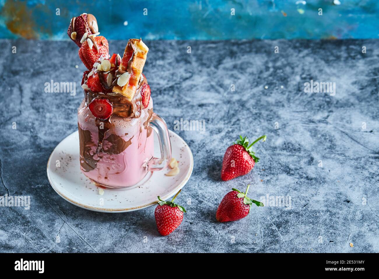 Erdbeer-Smoothie mit Waffeln und Schokolade auf dem weißen Teller Im Marmorhintergrund Stockfoto