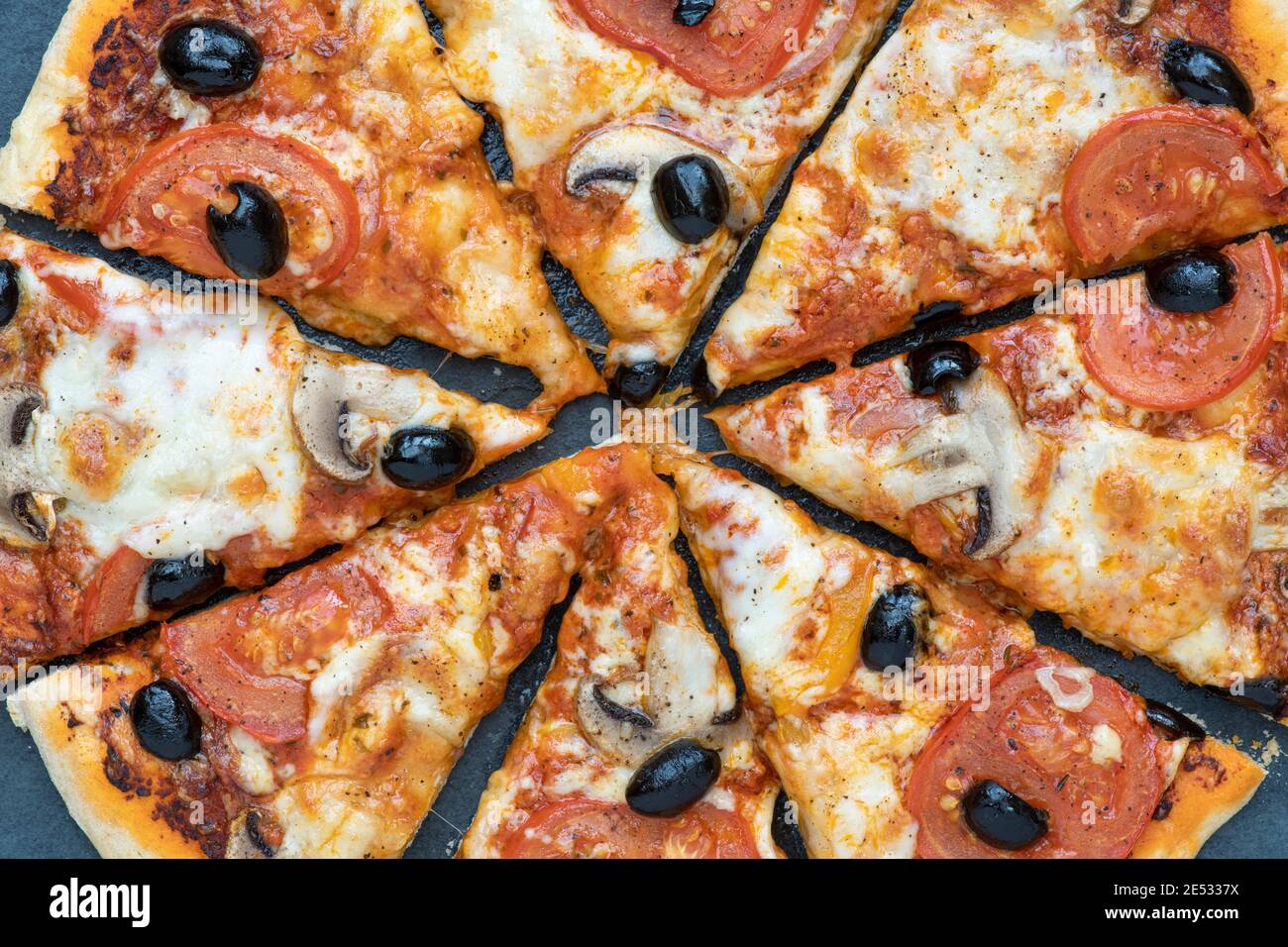 Hausgemachte vegetarische Tomaten- und Pilzpizza in Scheiben geschnitten Ein Schieferhintergrund Stockfoto