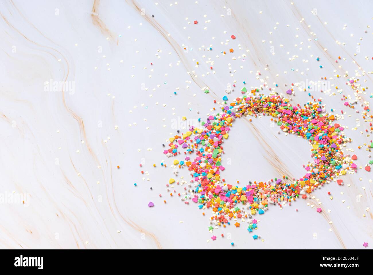 Herzform aus kleinen bunten Bonbons auf weißem Marmorboden. Valentinstag. Über Liebe. Hochwertige Fotos Stockfoto