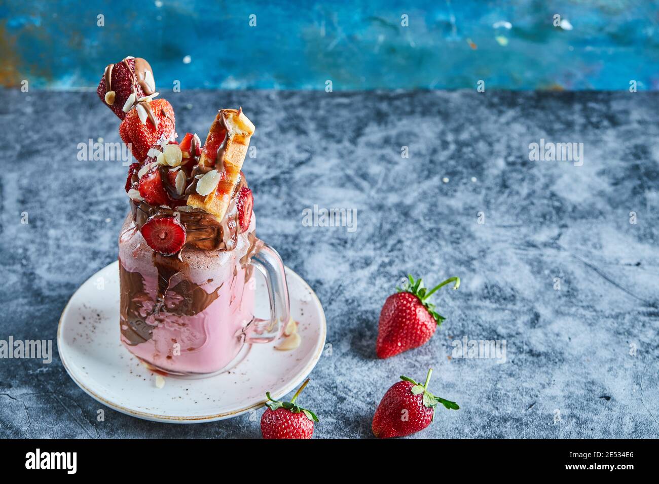 Erdbeer-Smoothie mit Waffeln und Schokolade auf dem weißen Teller Im Marmorhintergrund Stockfoto