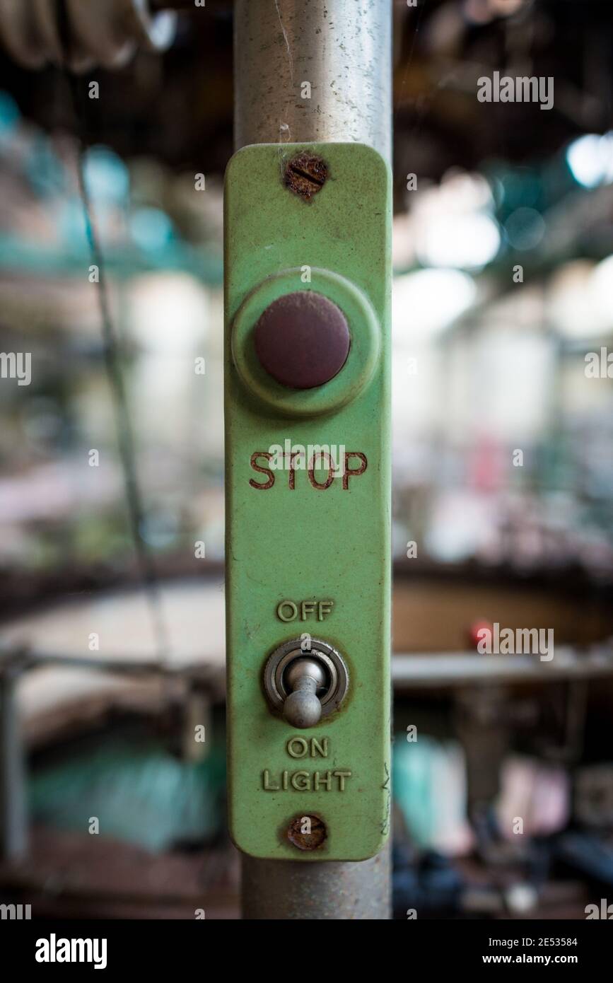 Symmetrische Nahaufnahme des Not-aus-Tasters an Industrielle Maschine in einem verlassenen italienischen Textilunternehmen Stockfoto