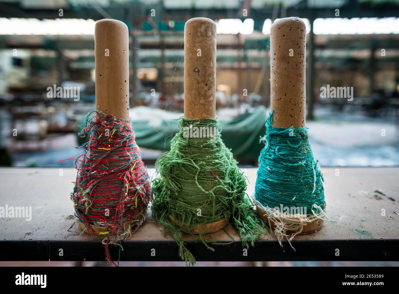 Nahaufnahme von drei bunten Fäden, die darauf liegen Ein Regal in einer verlassenen Textilfabrik Stockfoto