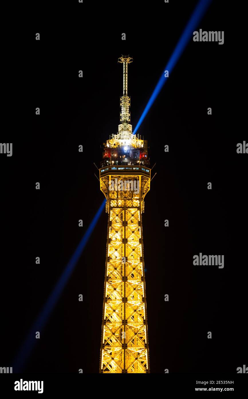 Nachtaufnahme des obersten Teils des Eiffelturms, wobei der Lichtstrahl diagonal leuchtet Stockfoto