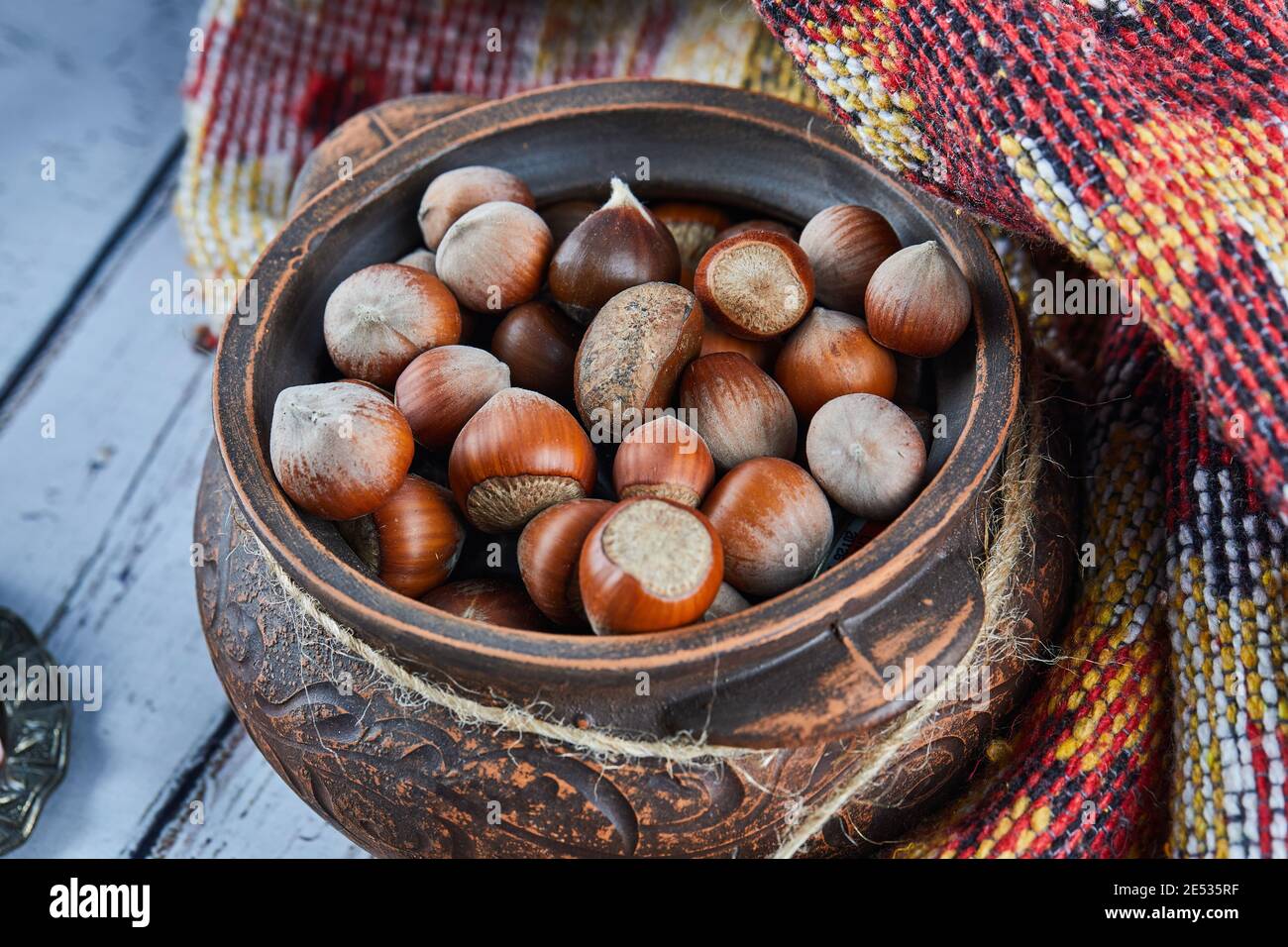 Eine Schale Haselnüsse auf blauem Holztisch mit geschnitzten Teppich Stockfoto