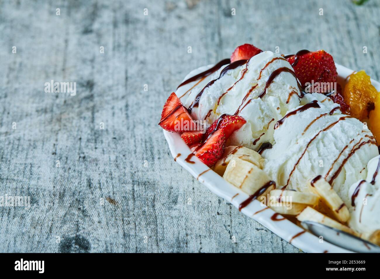 Eis mit Banane, Erdbeere, Orange, Schokolade auf dem weißen Teller Stockfoto