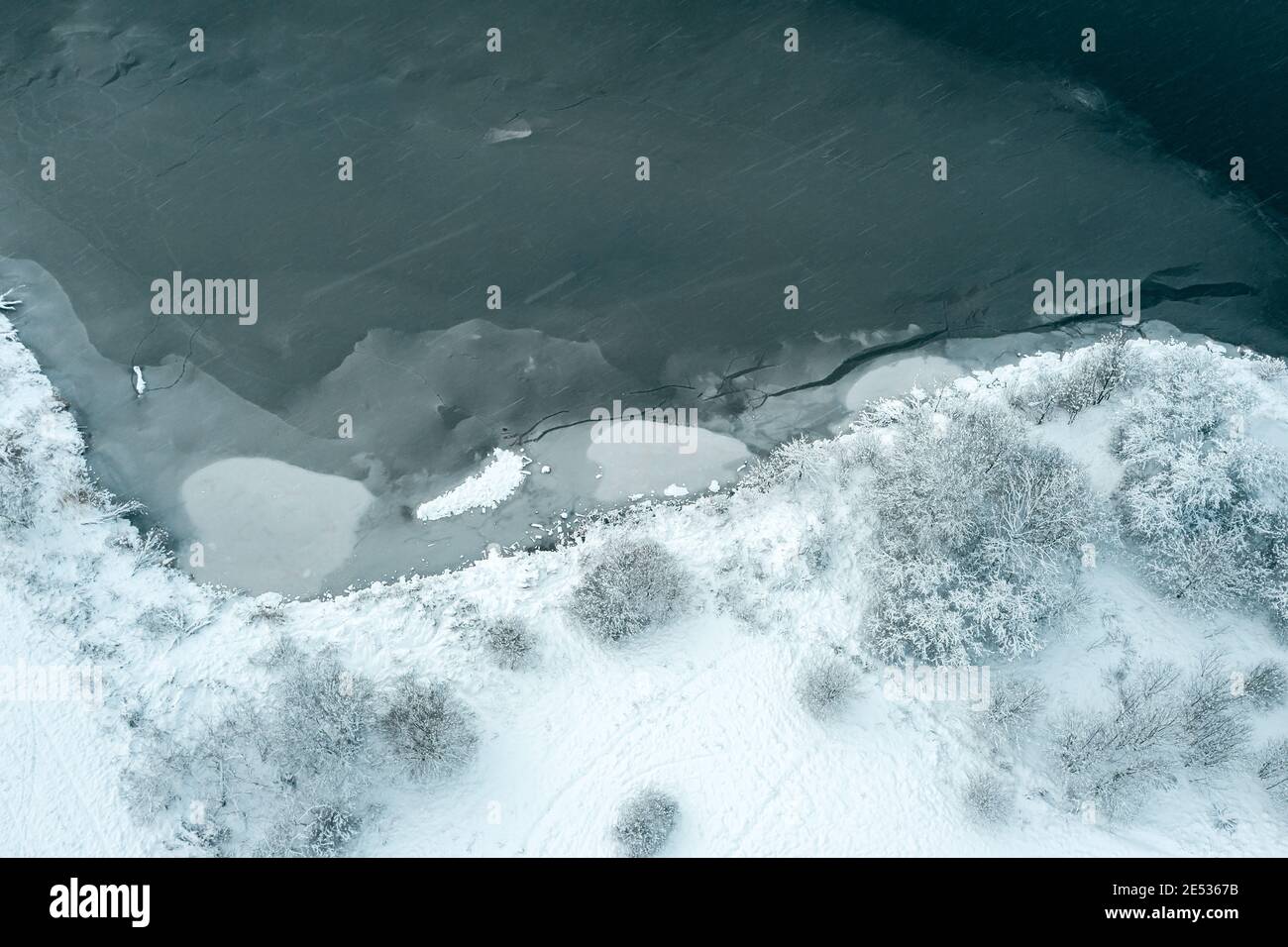 Luftaufnahme von gefrorenen See und schneebedeckten Bäumen an der Küste. Winter Hintergrund Stockfoto