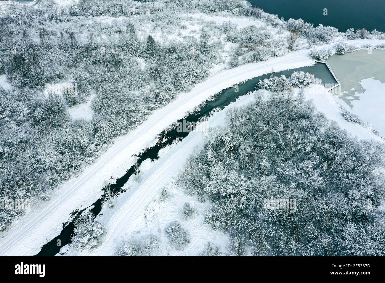 Luftaufnahme des gefrorenen Flusses im Winterwald mit schneebedeckten Bäumen. Winterlandschaft Stockfoto