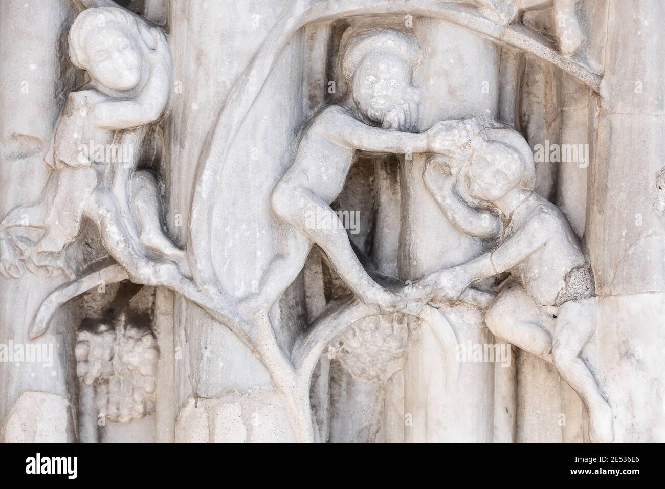 Nahaufnahme eines Flachreliefs aus weißem Marmor an der Fassade Der Kirche porträtiert drei Männer tragen einen Heiligenschein Stockfoto