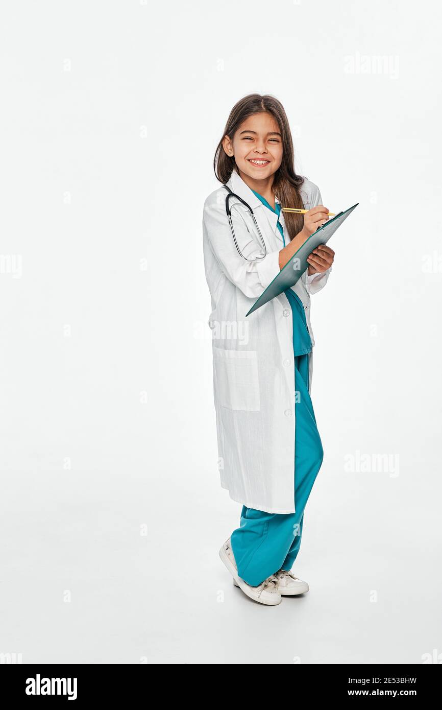 Kind spielt Arzt, zukünftiger Beruf. Cute hispanischen weiblichen Kind schreibt medizinische Behandlung auf ihre Zwischenablage. Weißer Hintergrund Stockfoto