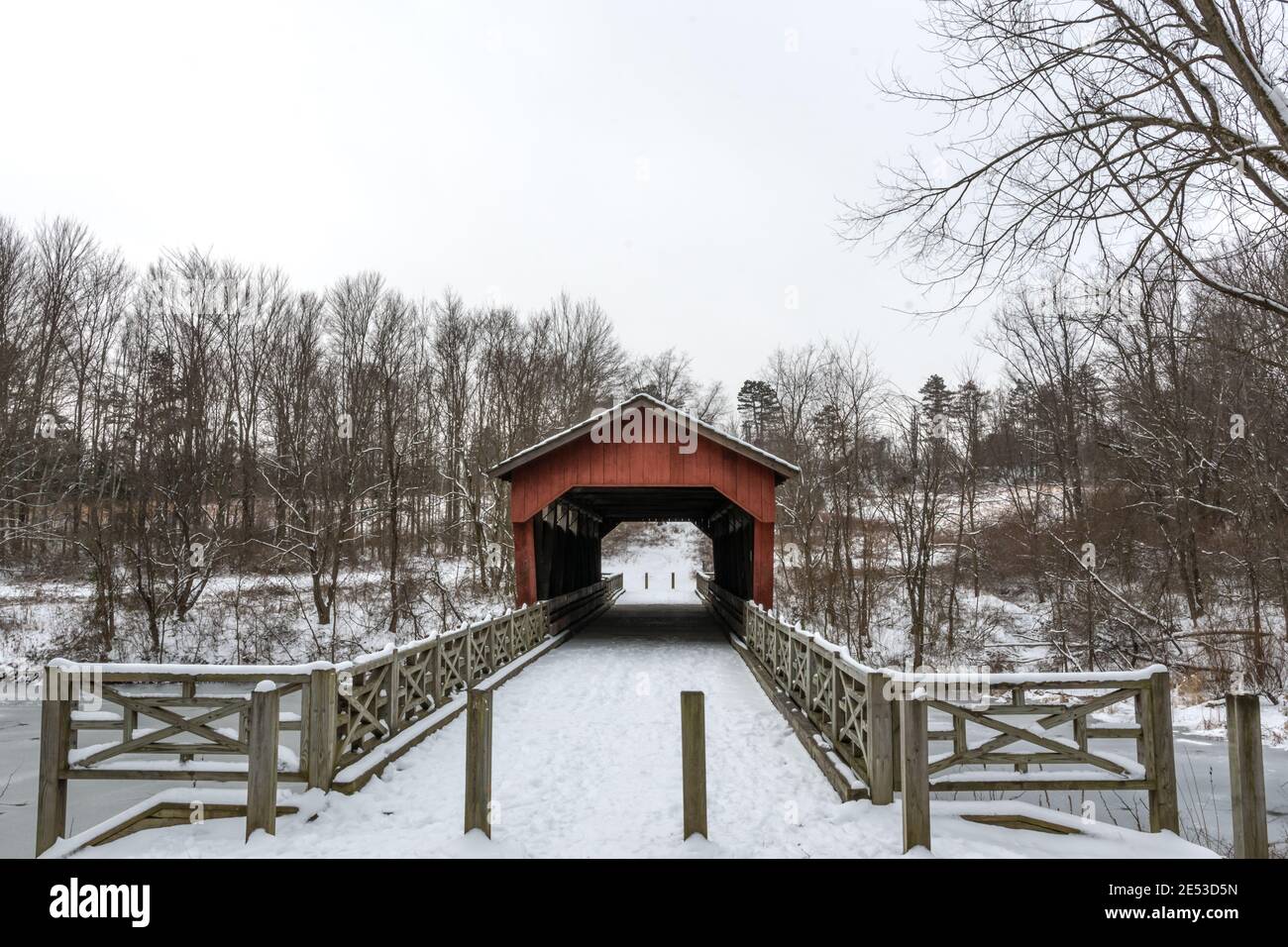 St. Clairsville, Ohio/USA - 15. Januar 2019: Schneebedeckte, historische Shaeffer Campbell Covered Bridge und der gefrorene College Pond mit umgebender Front Stockfoto
