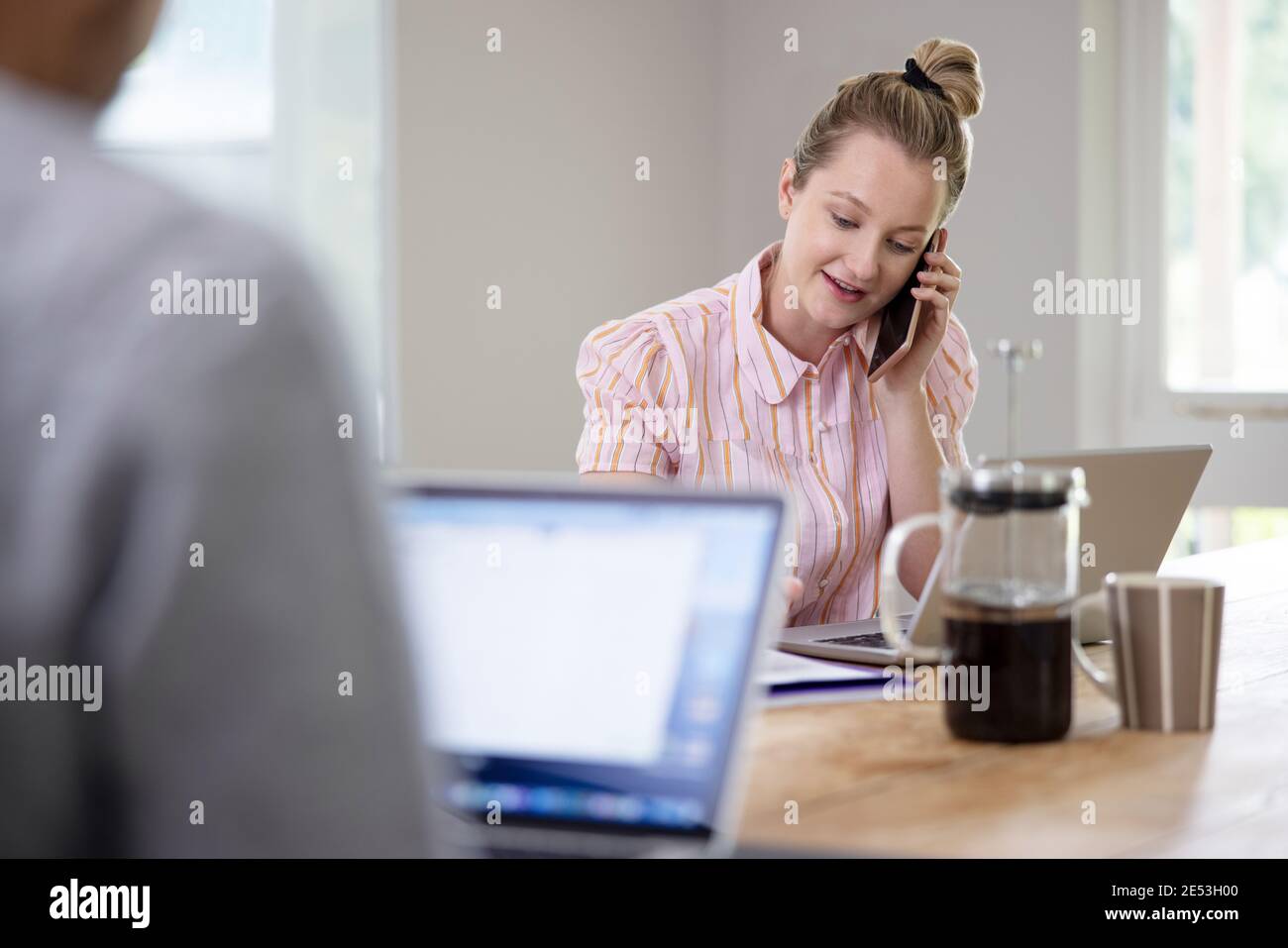 Geschäftspaar, Das Von Zu Hause Aus Während Der Pandemie Am Tisch Sitzt Sperrung Über Mobiltelefon Stockfoto