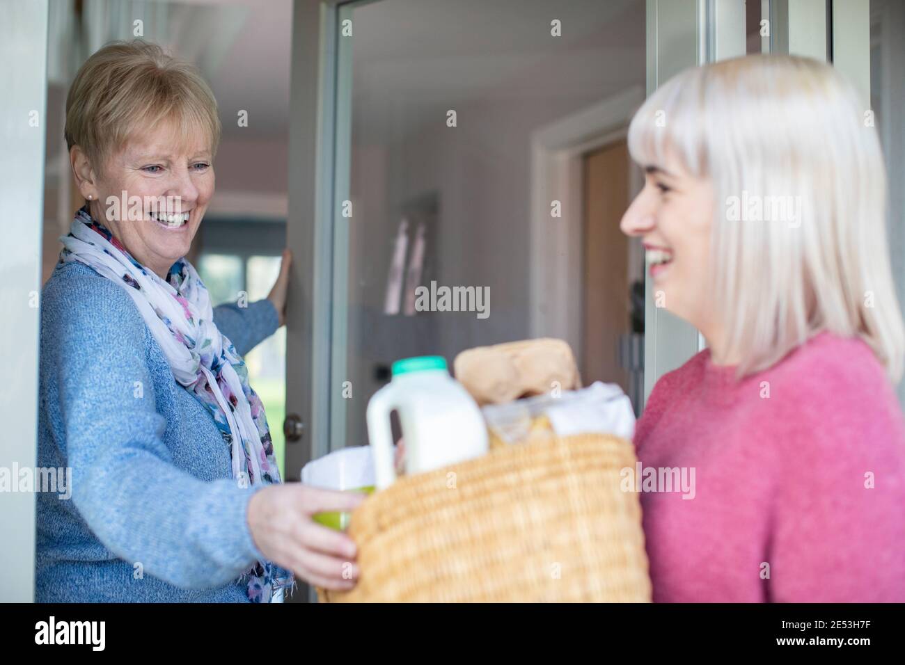 Nachbarin Hilft Älteren Frauen, Indem Sie Einkaufen Zu Hause Liefert Stockfoto