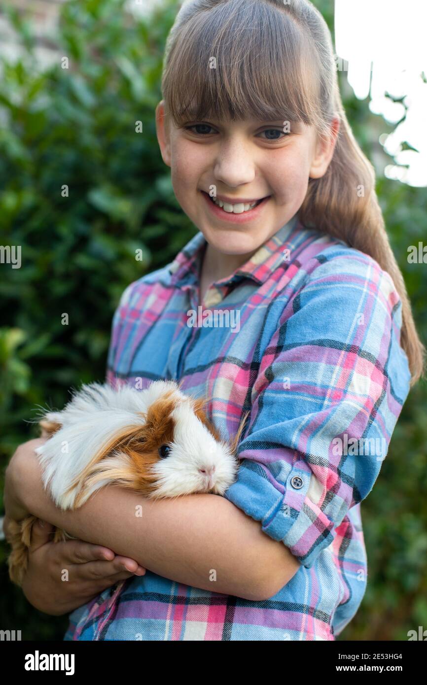 Portrait Of Girl Holding Pet Guinea Schwein Im Freien Im Garten Stockfoto