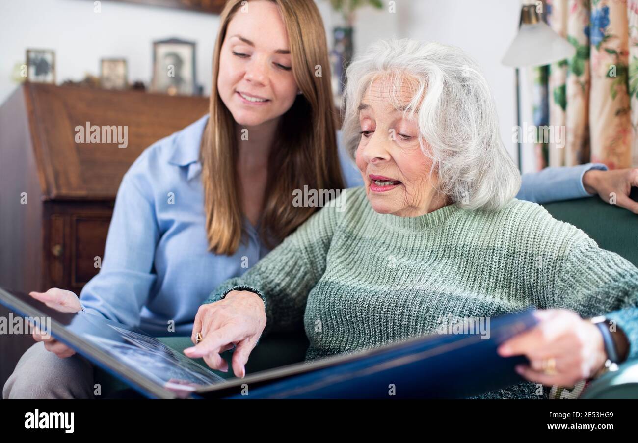 Großmutter Schaut Sich Fotoalbum Mit Erwachsenen Enkelin Zu Hause An Stockfoto