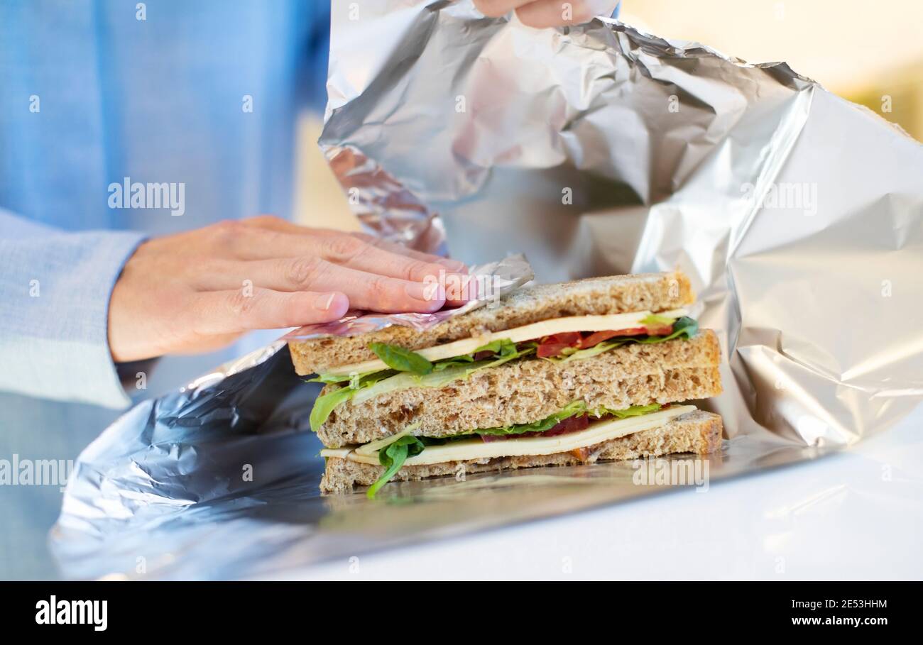 Nahaufnahme von Frau Verpackung Sandwich in nicht wiederverwendbaren Aluminiumfolie Stockfoto