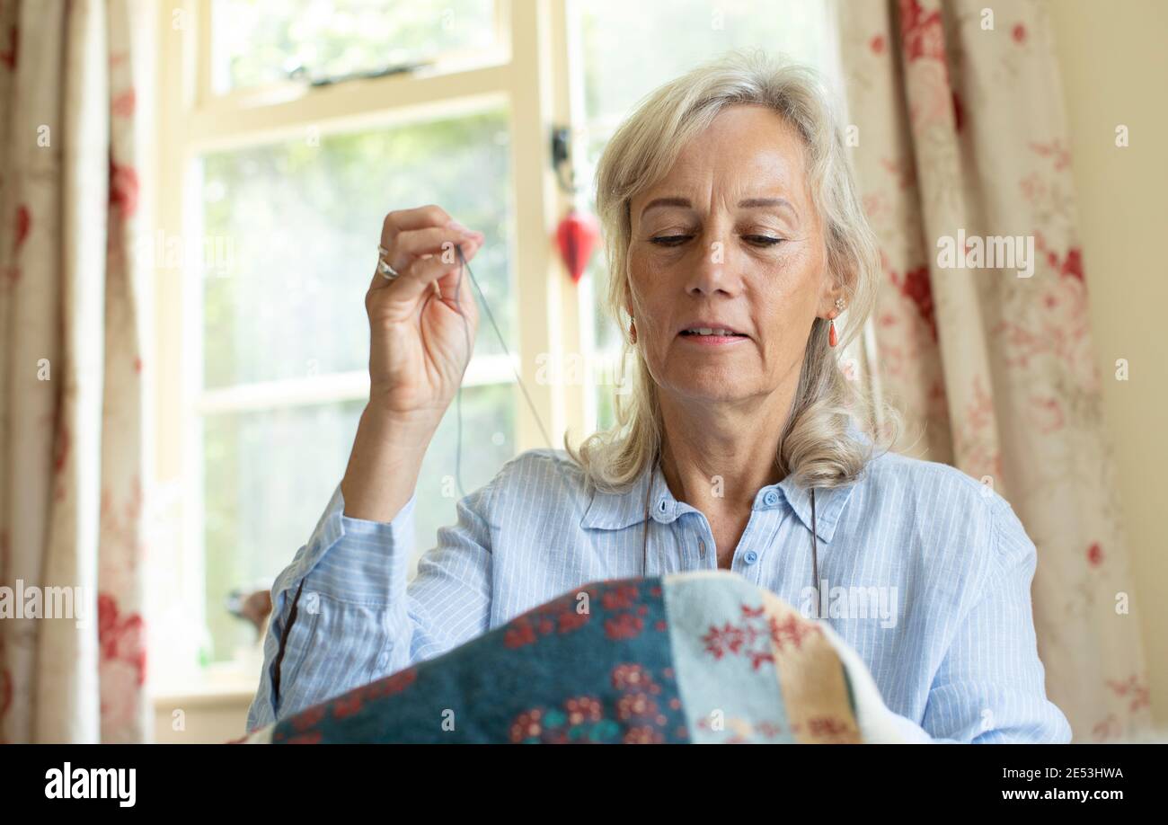 Ältere Frau Sticken Polsterbezüge zu Hause Stockfoto