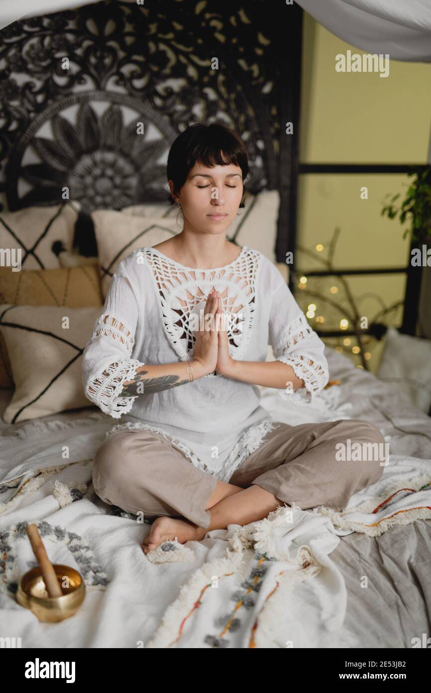 Schöne Brünette Frau auf dem Bett üben Meditation. Stockfoto