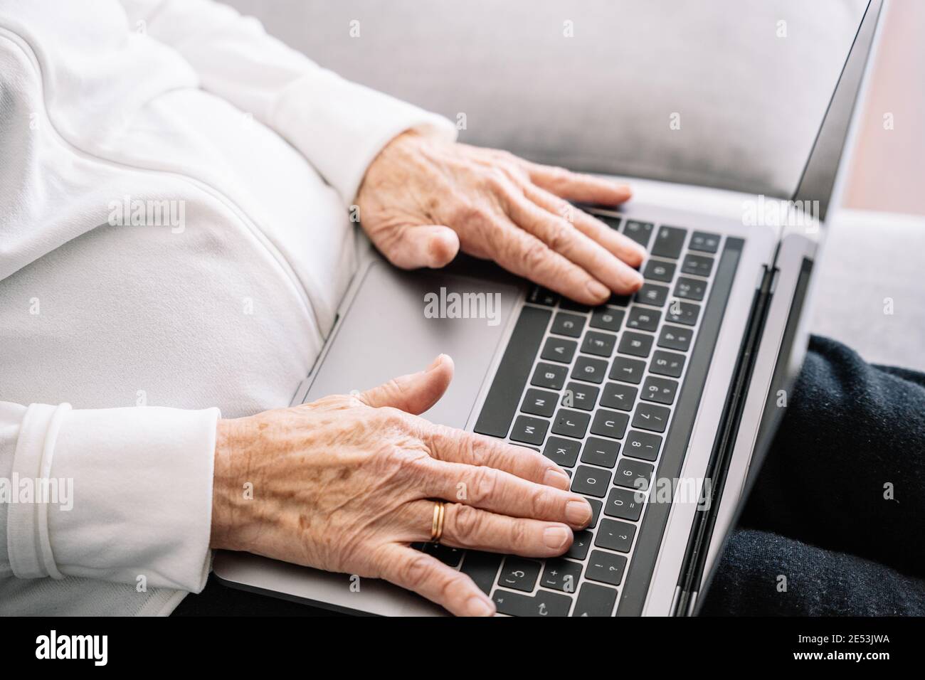 Hoher Winkel der Ernte anonyme ältere Frau auf dem Sofa sitzen Und beim Surfen im Netbook, während Sie sich am Wochenende zu Hause entspannen Stockfoto