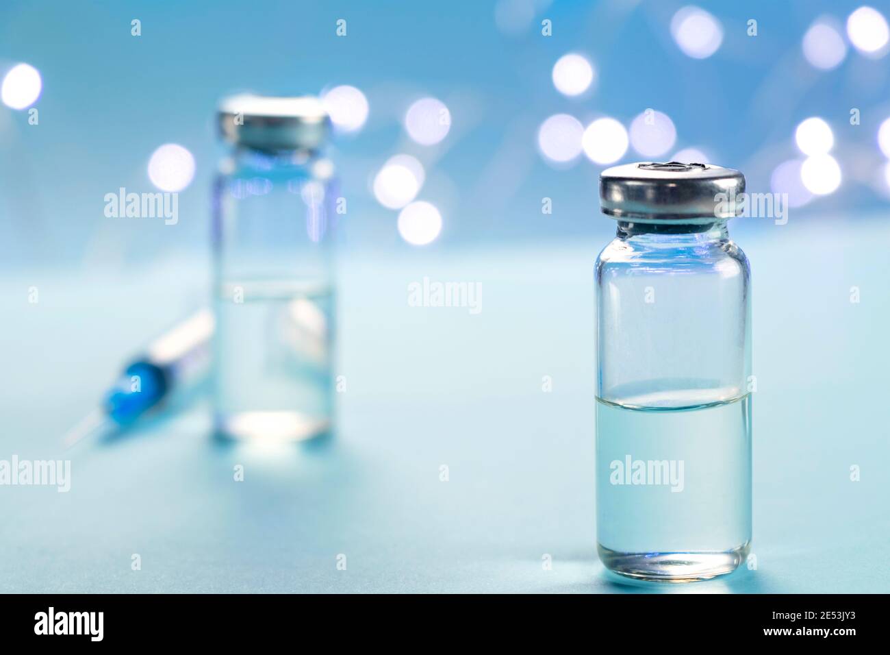 Zwei Flaschen Impfstoff und Spritzeninjektion auf blauem Hintergrund. Konzept der Prävention, Immunisierung und Behandlung von Infektionen. Infektiöse Medizin Stockfoto