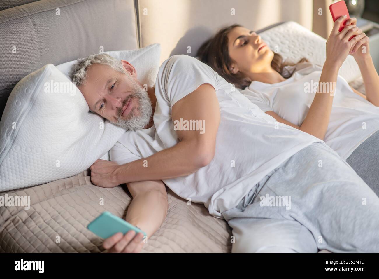 Frau und abgewandt Mann liegen mit Smartphones Stockfoto