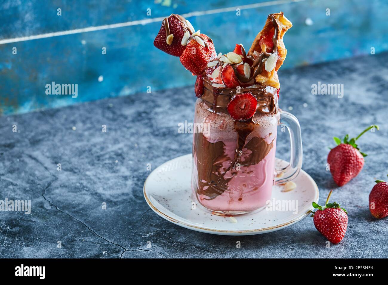 Erdbeer-Smoothie mit Waffeln und Schokolade auf dem weißen Teller Im Marmorhintergrund Stockfoto