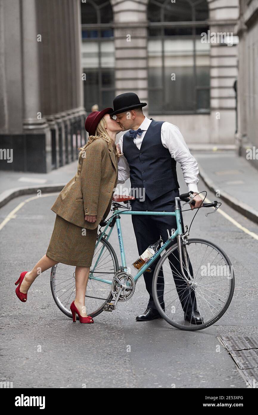 Leidenschaftlicher Mann auf dem Fahrrad hält und küsst Frau auf der Straße ,London, Großbritannien Stockfoto