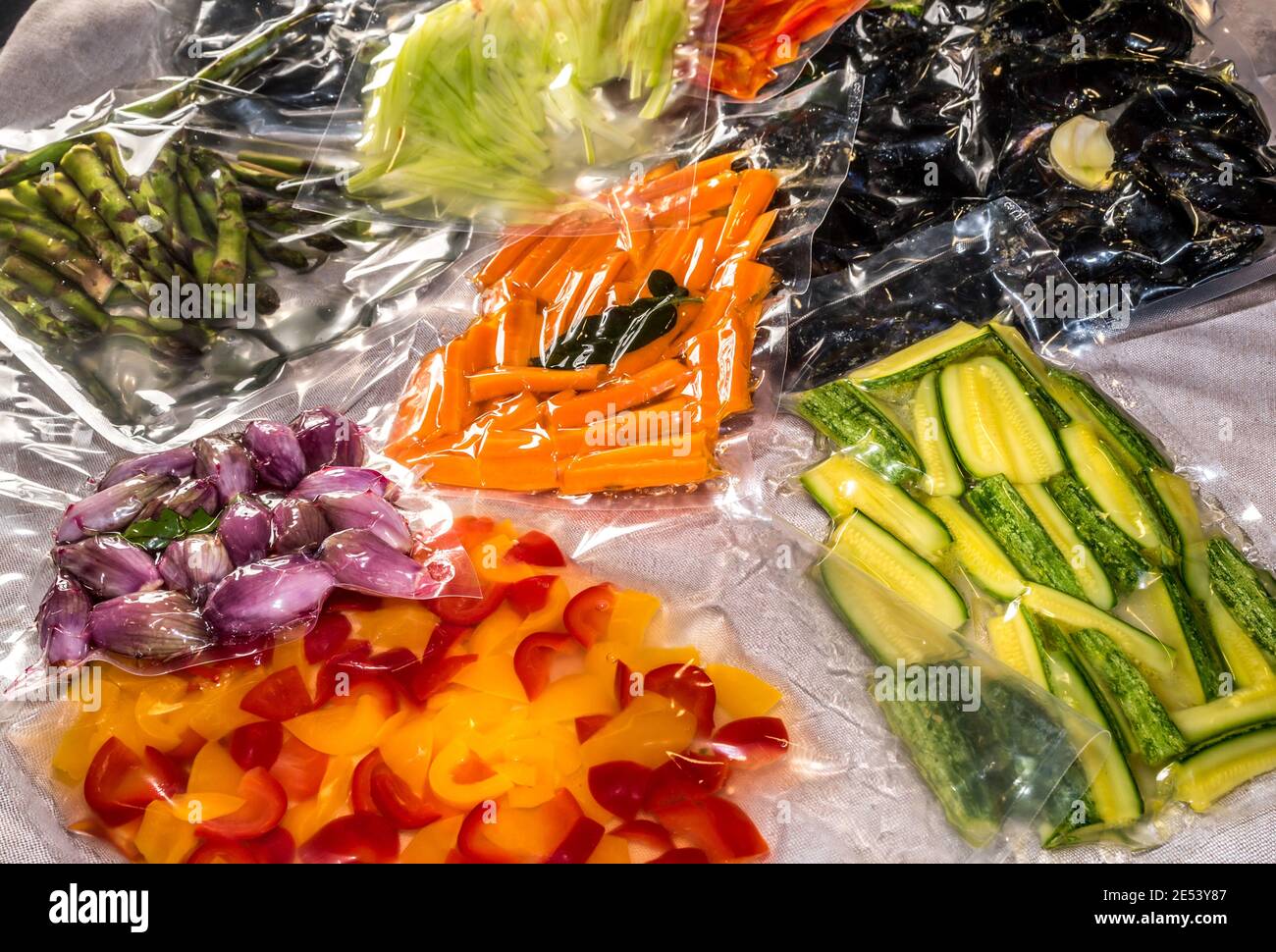 Versiegelte Beutel zum Sous-Vide-Kochen mit Paprika und Zucchini und Schalotten, frischen Karotten und Spargel und Muscheln Stockfoto