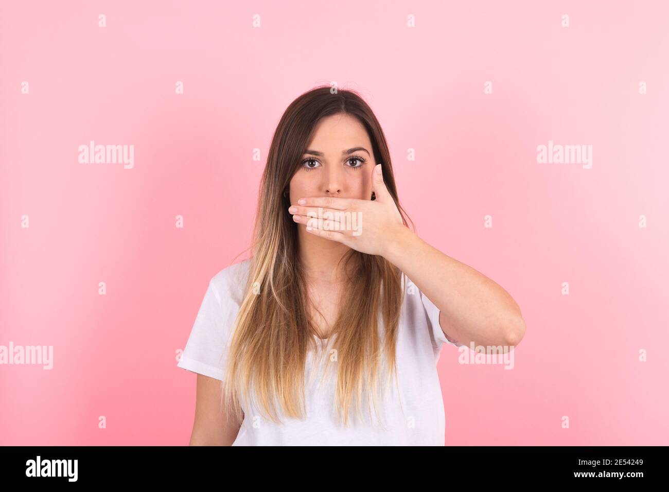 Junge Frau bedeckt ihren Mund mit ihrer Hand mit einem Ernste Geste Stockfoto