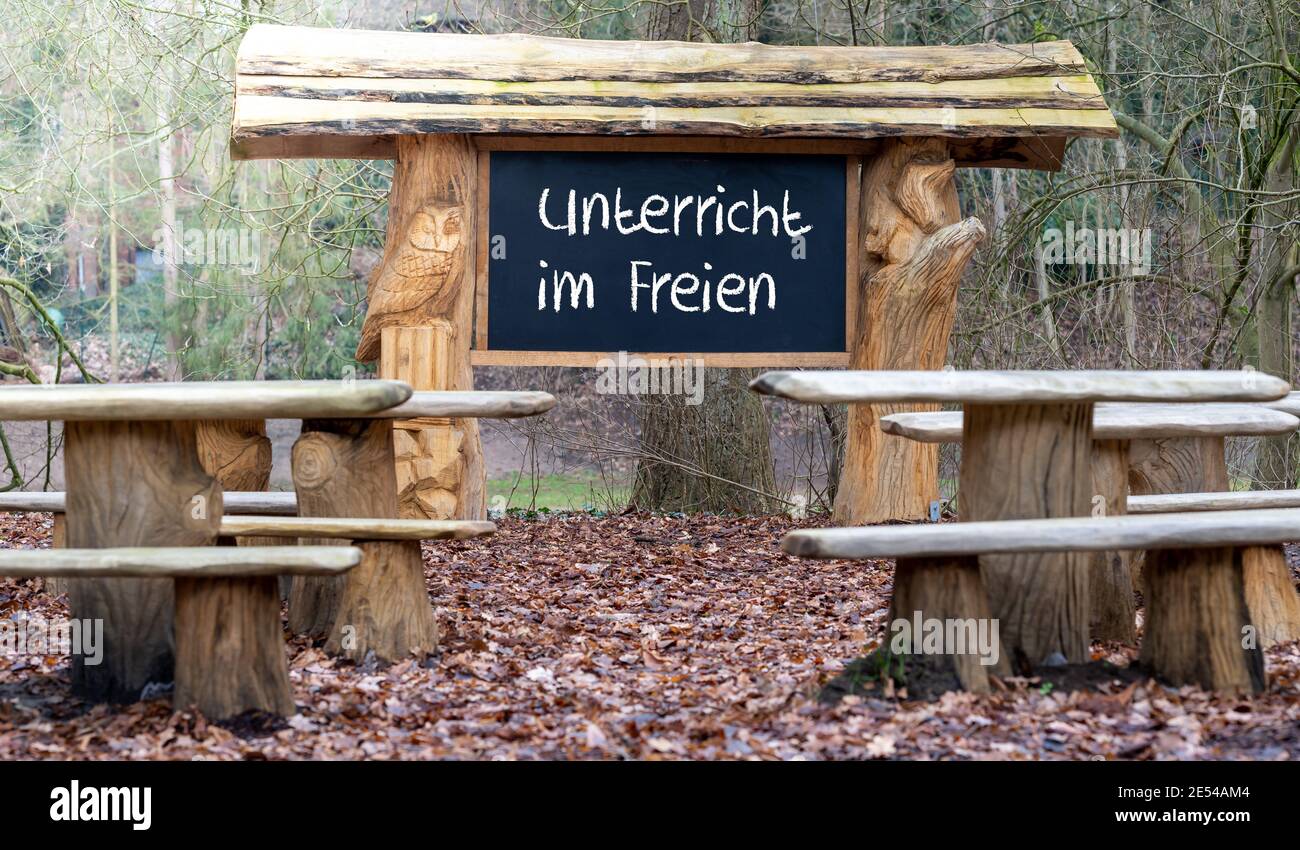 Ein Klassenzimmer im Wald. Unterricht während der Corona-Pandemie. Die Tafel zeigt den deutschen Text 'Unterricht im freien'. Stockfoto