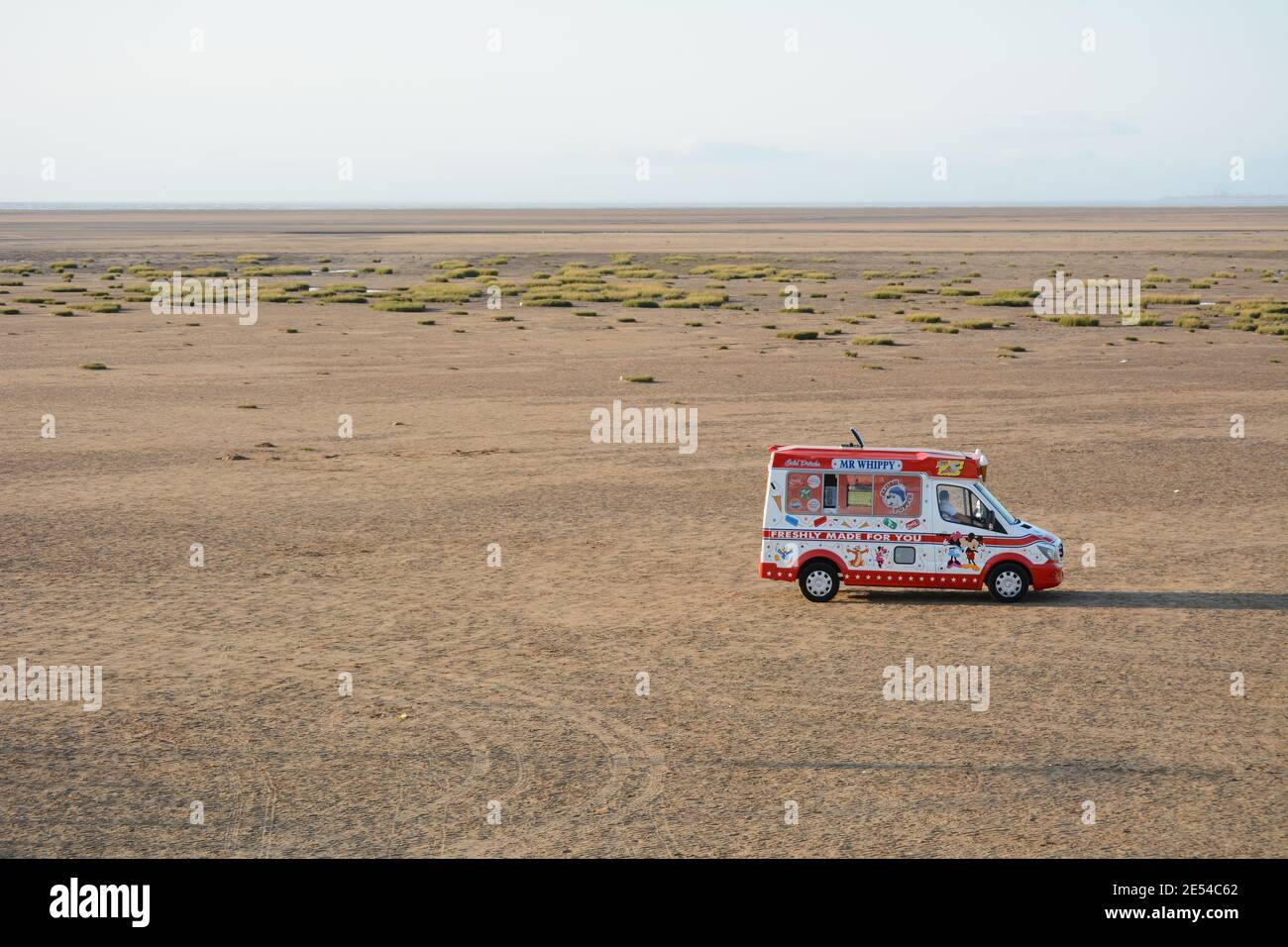 Rot-weißer Mr Whippy Eiswagen auf Southport Strand bei Ebbe mit langem Schatten im sonnigen Sommer Abend 2020 Stockfoto