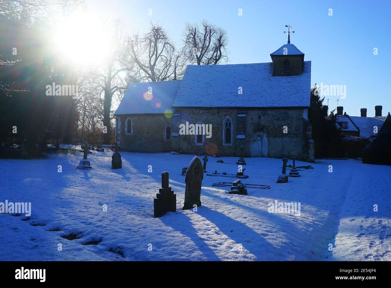 Niedrige Wintersonne strahlt auf der verschneiten Kirche der Heiligen Jungfrau Maria, Letchworth Stockfoto