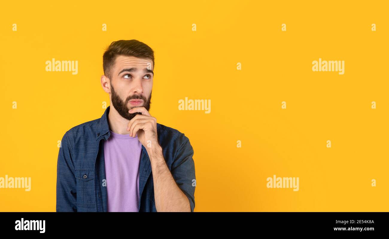 Verträumt kaukasischen Kerl denken über etwas, berühren sein Kinn auf orangefarbenem Hintergrund, Banner-Design mit Copy Space Stockfoto