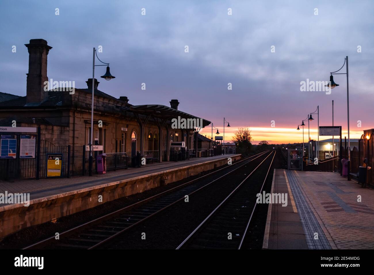 Mansfield Stadt Nottinghamshire Bahnhof bei Sonnenaufgang mit Sonne Am Horizont über Robin Hood Line mit leerer Plattform Und traditionellen Stein Stockfoto