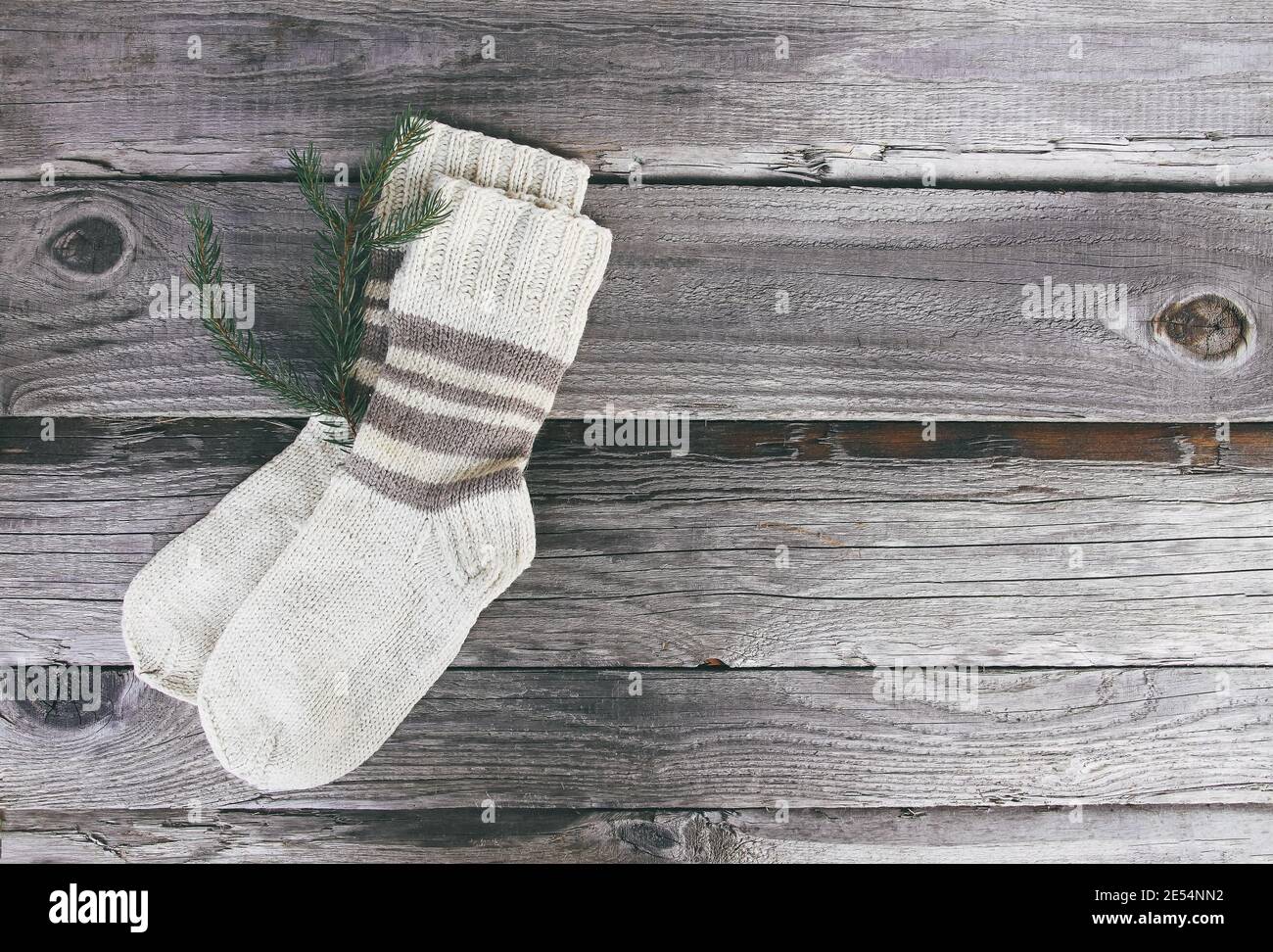 Handgemachte warme Stricksocken aus Wollgarn auf Holz rauem Hintergrund. Stockfoto